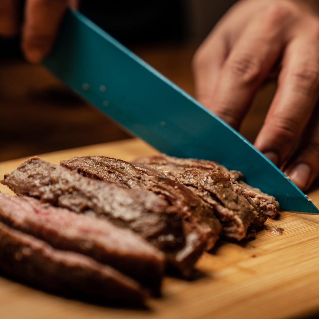 person slicing chocolate cake on green chopping board