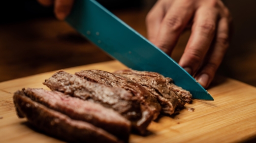 person slicing chocolate cake on green chopping board